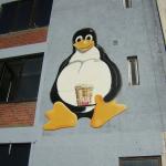 Down by the river there was this giant Tux with a beer on the side of this cafe

